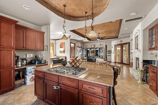 kitchen featuring wine cooler, a textured ceiling, stainless steel gas stovetop, a tray ceiling, and a kitchen bar