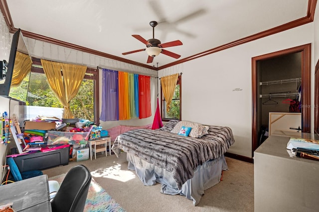 bedroom with a closet, crown molding, ceiling fan, a walk in closet, and light carpet