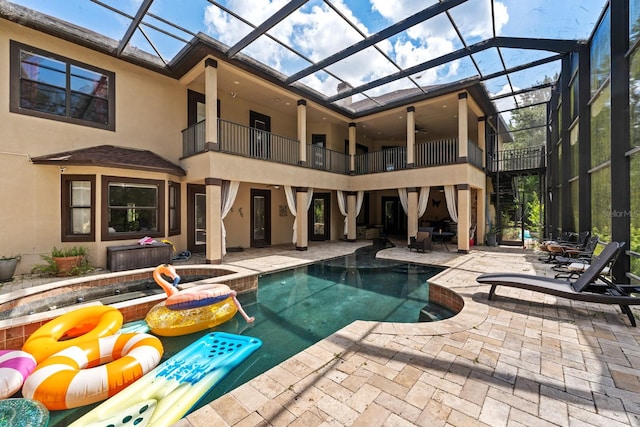 view of swimming pool featuring glass enclosure, a patio area, and a hot tub