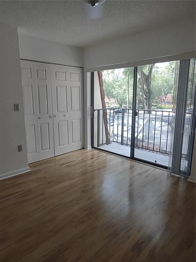 interior space with access to outside, a closet, hardwood / wood-style floors, and a textured ceiling