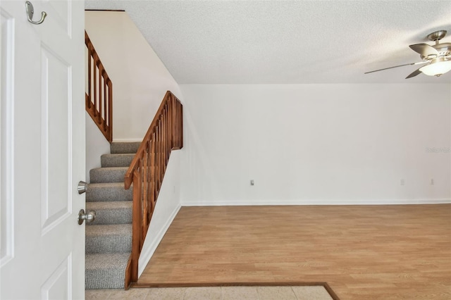 stairway featuring ceiling fan, hardwood / wood-style flooring, and a textured ceiling