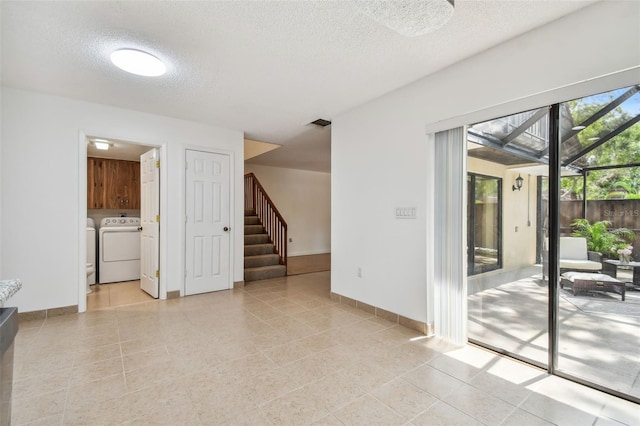 tiled spare room featuring a textured ceiling and washing machine and dryer