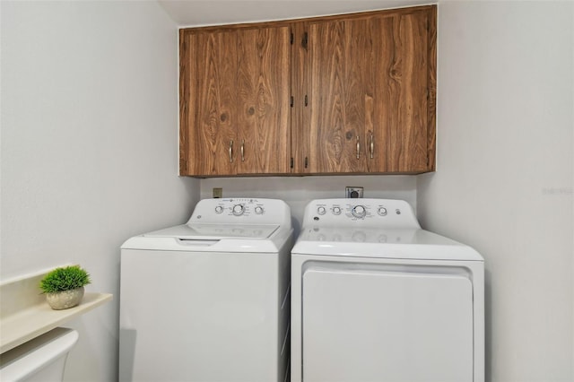 clothes washing area featuring separate washer and dryer and cabinets