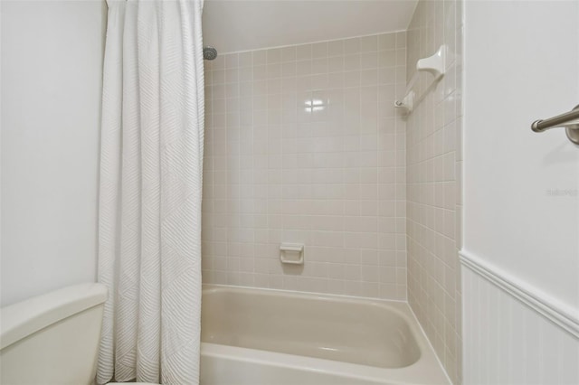 bathroom featuring toilet and shower / tub combo with curtain