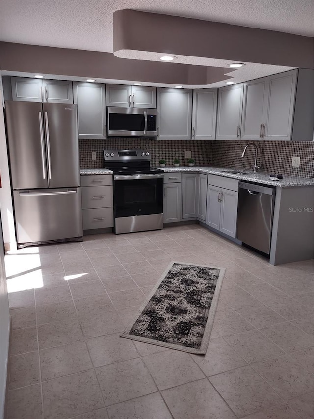 kitchen featuring stainless steel appliances, decorative backsplash, sink, and gray cabinets