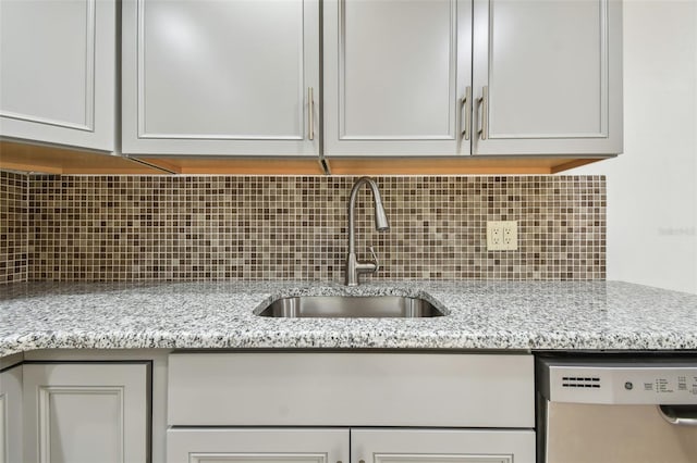 kitchen with stainless steel dishwasher, sink, light stone countertops, and decorative backsplash