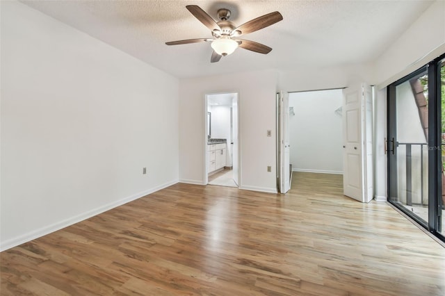 unfurnished bedroom featuring light hardwood / wood-style flooring, a textured ceiling, ensuite bathroom, and ceiling fan