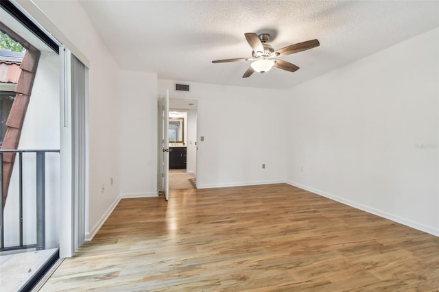 empty room featuring a textured ceiling, light hardwood / wood-style floors, and ceiling fan