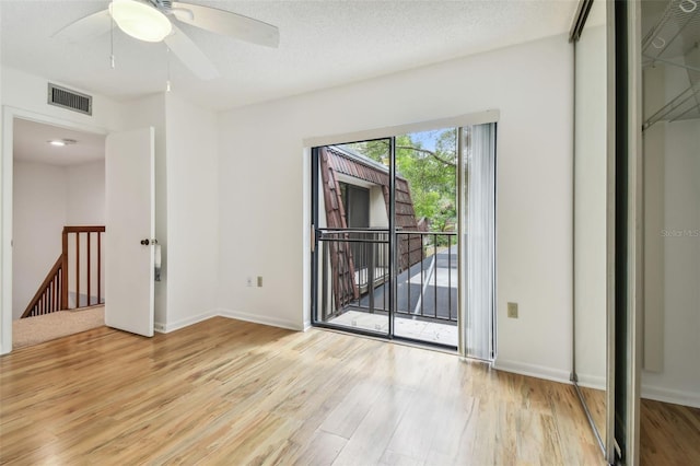 unfurnished room featuring a textured ceiling, light wood-type flooring, and ceiling fan