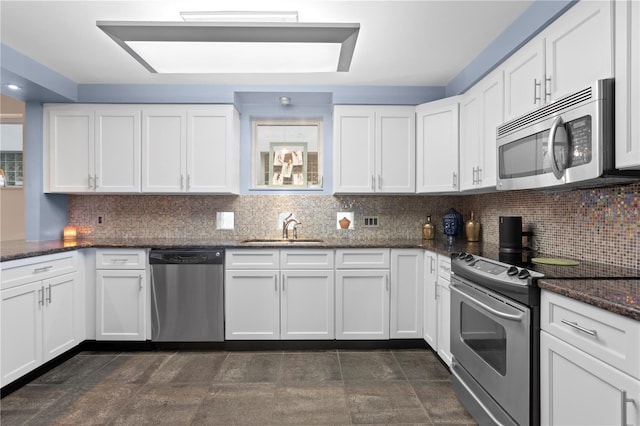 kitchen featuring appliances with stainless steel finishes, backsplash, dark stone counters, sink, and white cabinets