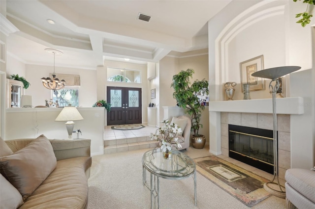 living room with an inviting chandelier, ornamental molding, a tiled fireplace, and carpet