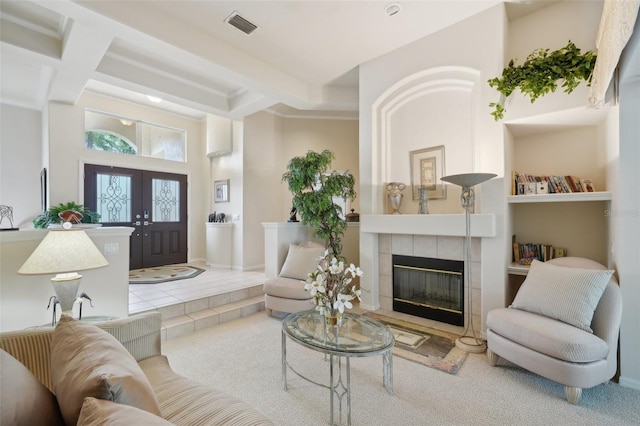 carpeted living room featuring french doors, beam ceiling, and a tile fireplace