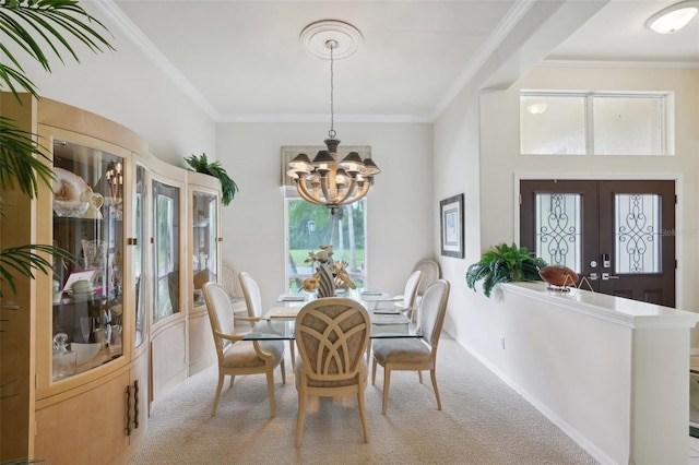 carpeted dining area featuring french doors, ornamental molding, a wealth of natural light, and a chandelier