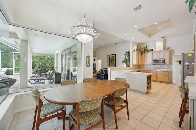 tiled dining area featuring a chandelier and a tray ceiling