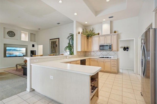 kitchen featuring backsplash, kitchen peninsula, light carpet, stainless steel appliances, and light brown cabinets