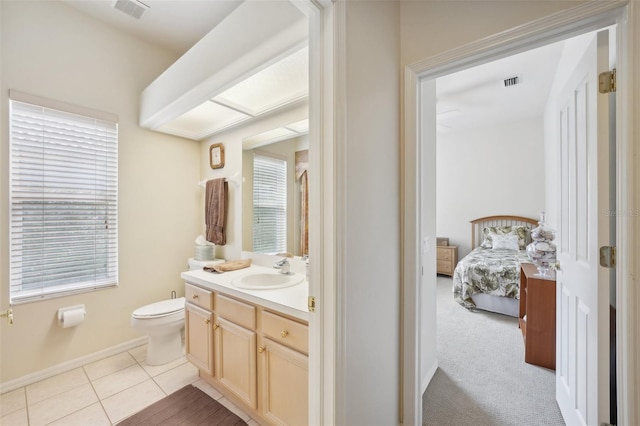 bathroom with a healthy amount of sunlight, vanity, toilet, and tile patterned floors