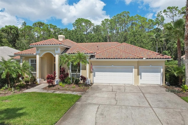 mediterranean / spanish-style home featuring a front lawn and a garage