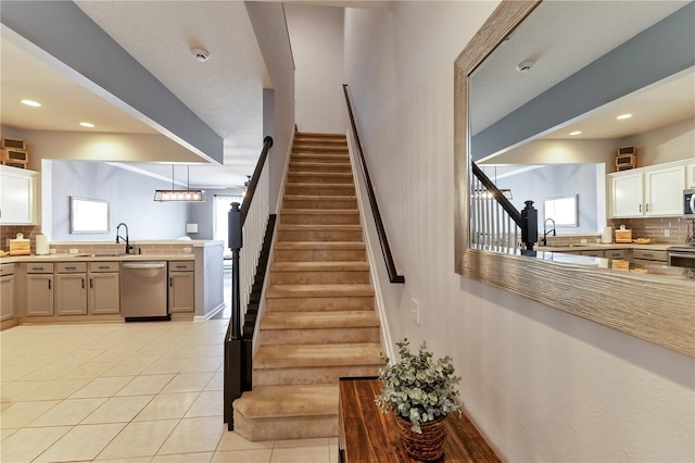 staircase featuring tile patterned flooring, sink, and plenty of natural light