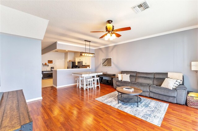 living room with ornamental molding, ceiling fan, hardwood / wood-style floors, and a textured ceiling