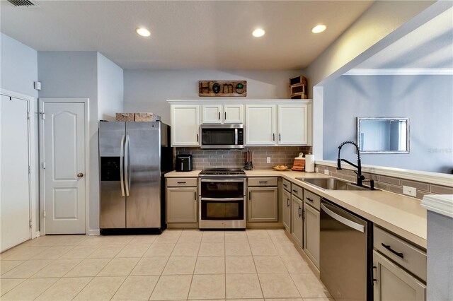 kitchen featuring light tile patterned flooring, sink, tasteful backsplash, white cabinetry, and stainless steel appliances