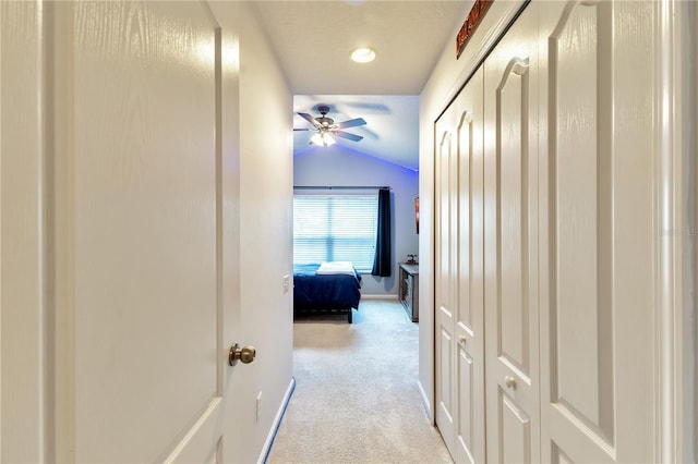 hallway with light colored carpet and lofted ceiling