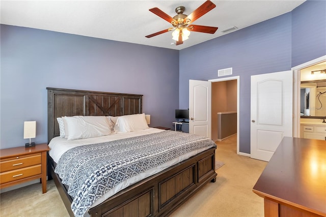 bedroom featuring light carpet, ensuite bath, and ceiling fan