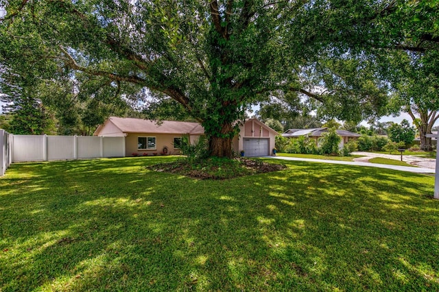 ranch-style home featuring driveway, a front lawn, an attached garage, and fence