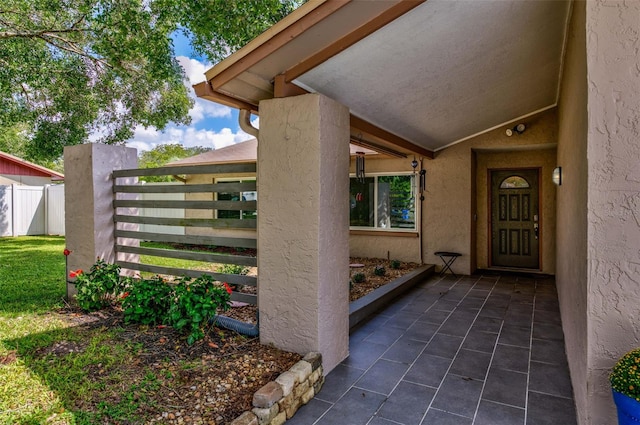 entrance to property featuring fence and stucco siding