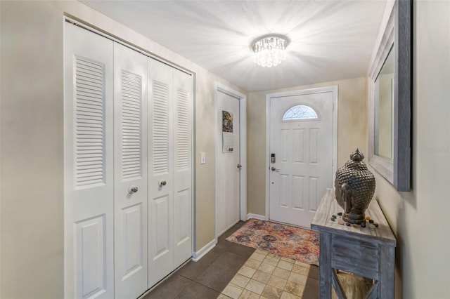 tiled entrance foyer with baseboards and an inviting chandelier