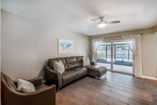 living area featuring ceiling fan, baseboards, and tile patterned floors