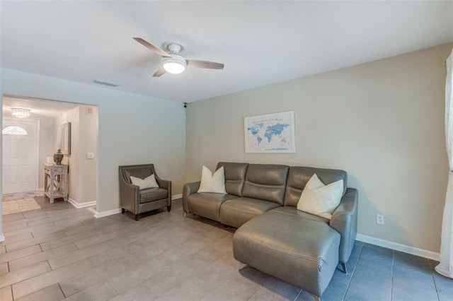 living room with baseboards, visible vents, and ceiling fan