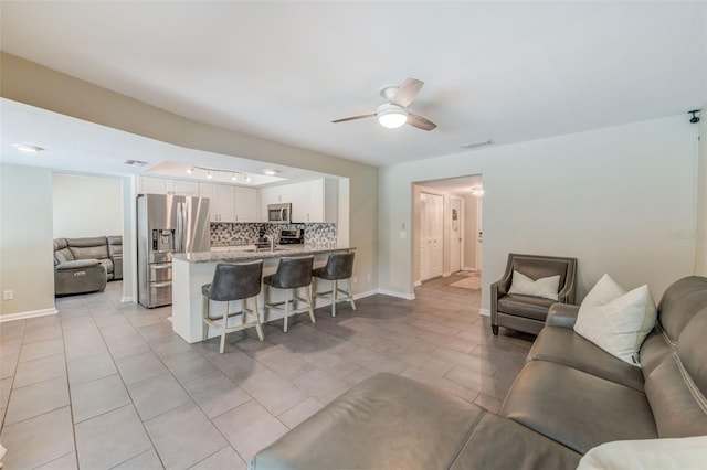 living area with visible vents, ceiling fan, baseboards, and light tile patterned floors