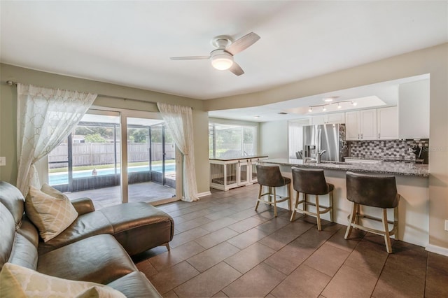 kitchen with a peninsula, white cabinetry, a kitchen breakfast bar, backsplash, and stainless steel fridge with ice dispenser