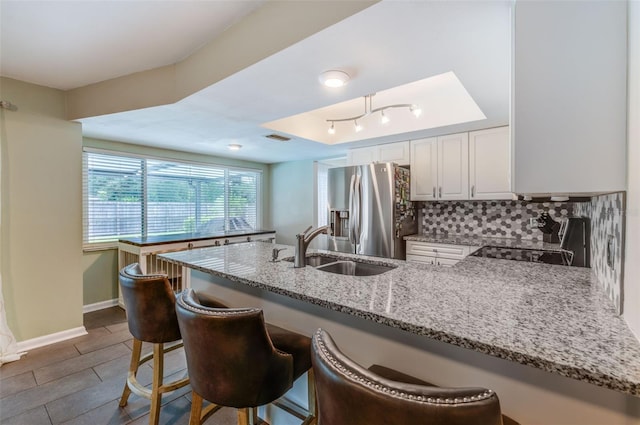 kitchen with stainless steel fridge, electric range, a raised ceiling, a peninsula, and backsplash