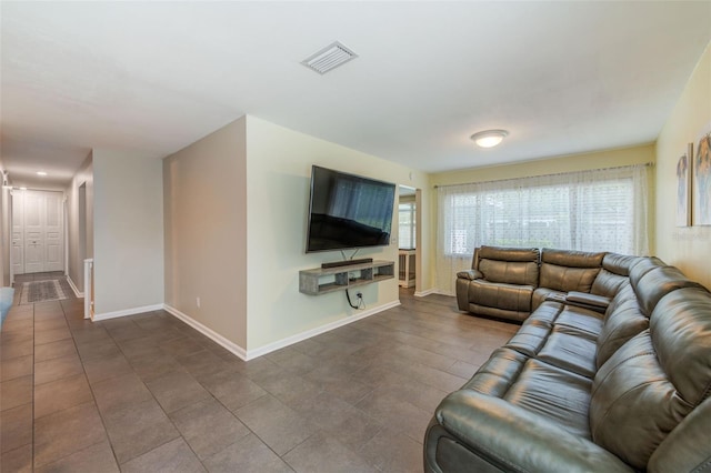 living area featuring dark tile patterned floors, visible vents, and baseboards