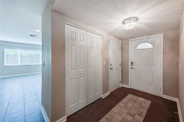 entryway featuring a chandelier, tile patterned flooring, visible vents, and baseboards