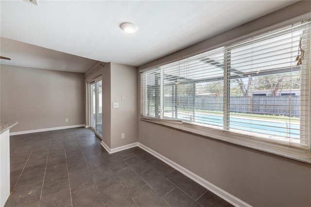 unfurnished room with plenty of natural light and baseboards