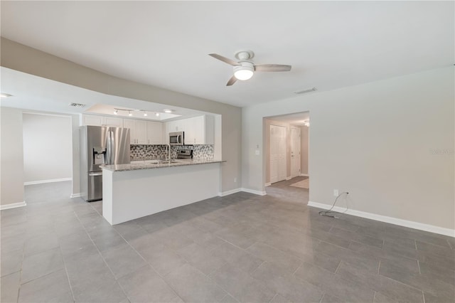 interior space featuring a sink, baseboards, visible vents, and a ceiling fan