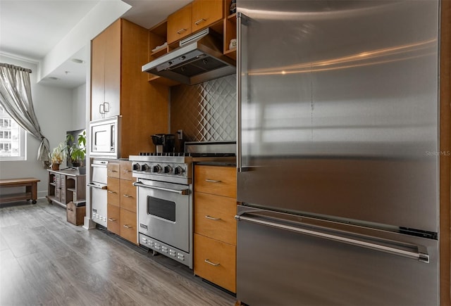 kitchen with decorative backsplash, dark wood-type flooring, extractor fan, and high quality appliances