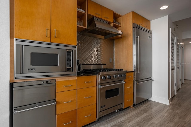 kitchen featuring high quality appliances, hardwood / wood-style floors, and decorative backsplash