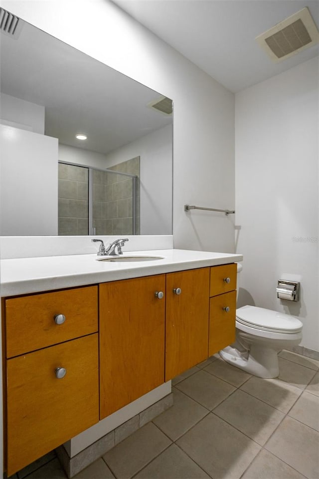 bathroom featuring vanity, tile patterned flooring, toilet, and a shower with door