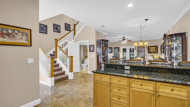 kitchen featuring crown molding, dark stone countertops, ceiling fan, and decorative light fixtures