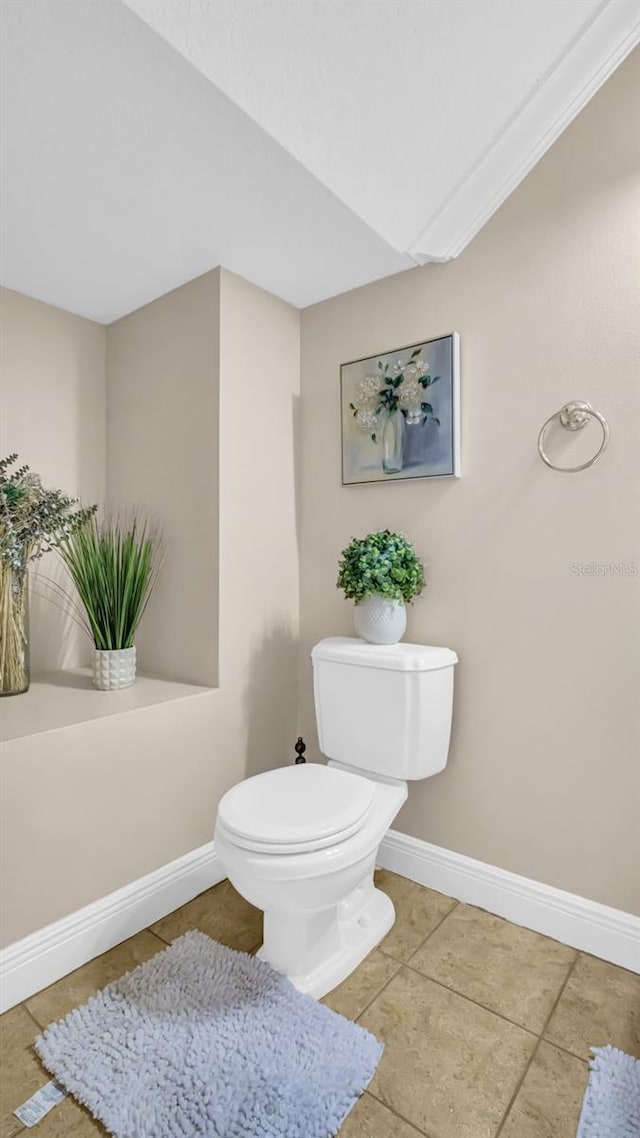 bathroom with crown molding, toilet, and tile patterned floors