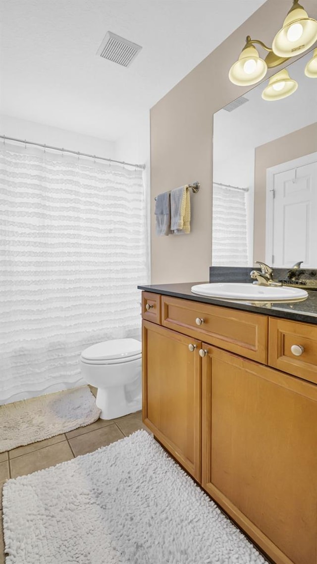 bathroom with a shower with curtain, vanity, toilet, and tile patterned floors