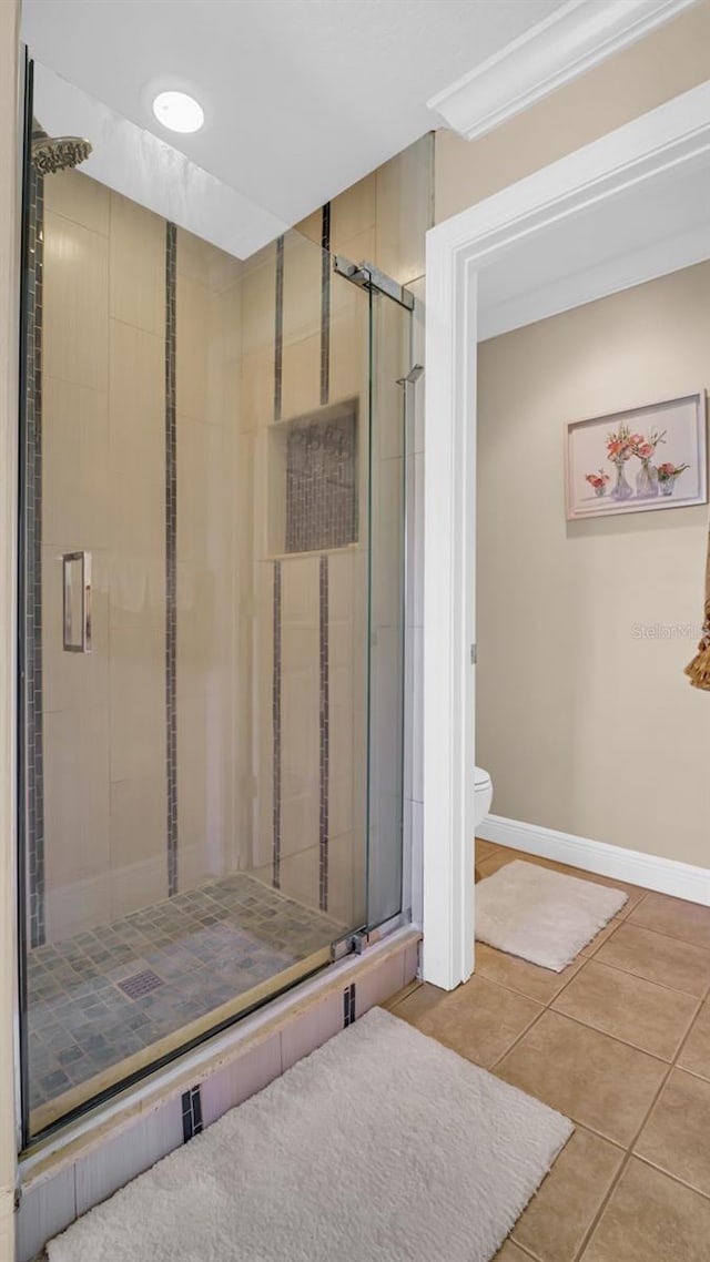 bathroom featuring tile patterned flooring, toilet, and an enclosed shower