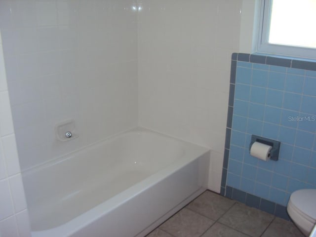 bathroom with tile patterned flooring, tile walls, and toilet