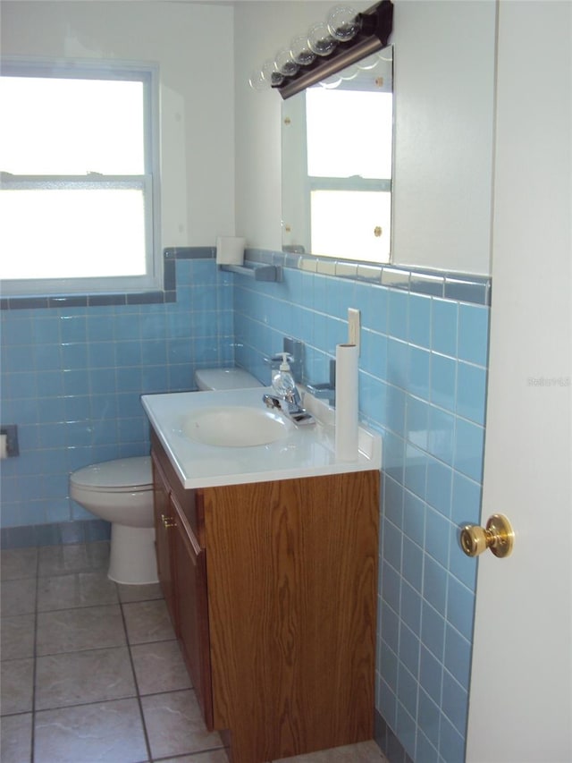 bathroom featuring tile patterned flooring, vanity, tile walls, and toilet