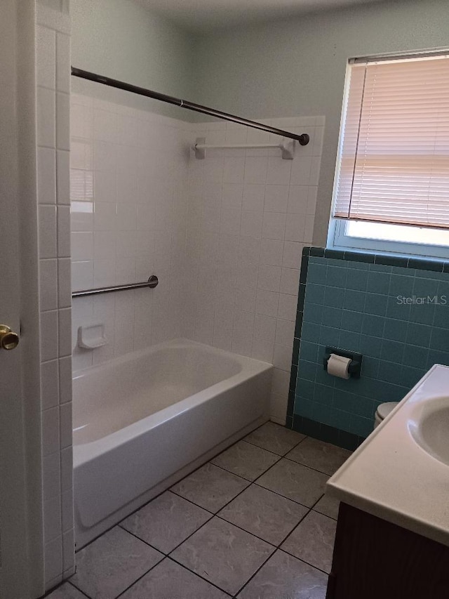 bathroom with tile patterned floors, vanity, tile walls, and tiled shower / bath