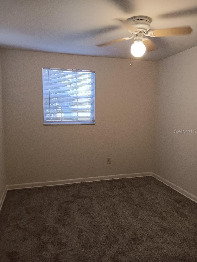 empty room with dark colored carpet and ceiling fan