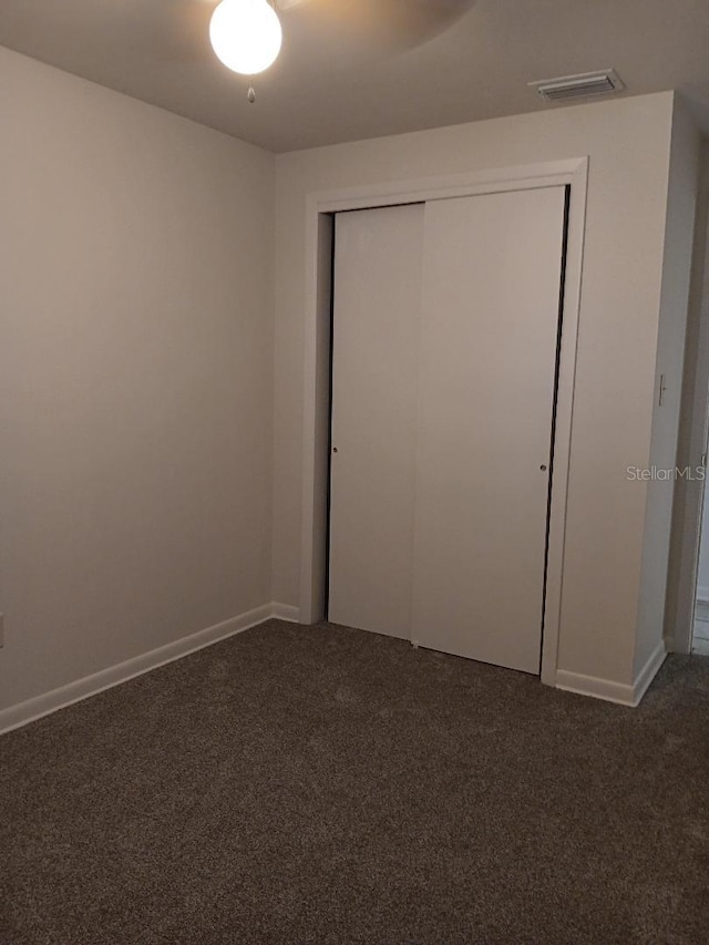 unfurnished bedroom with a closet and dark colored carpet